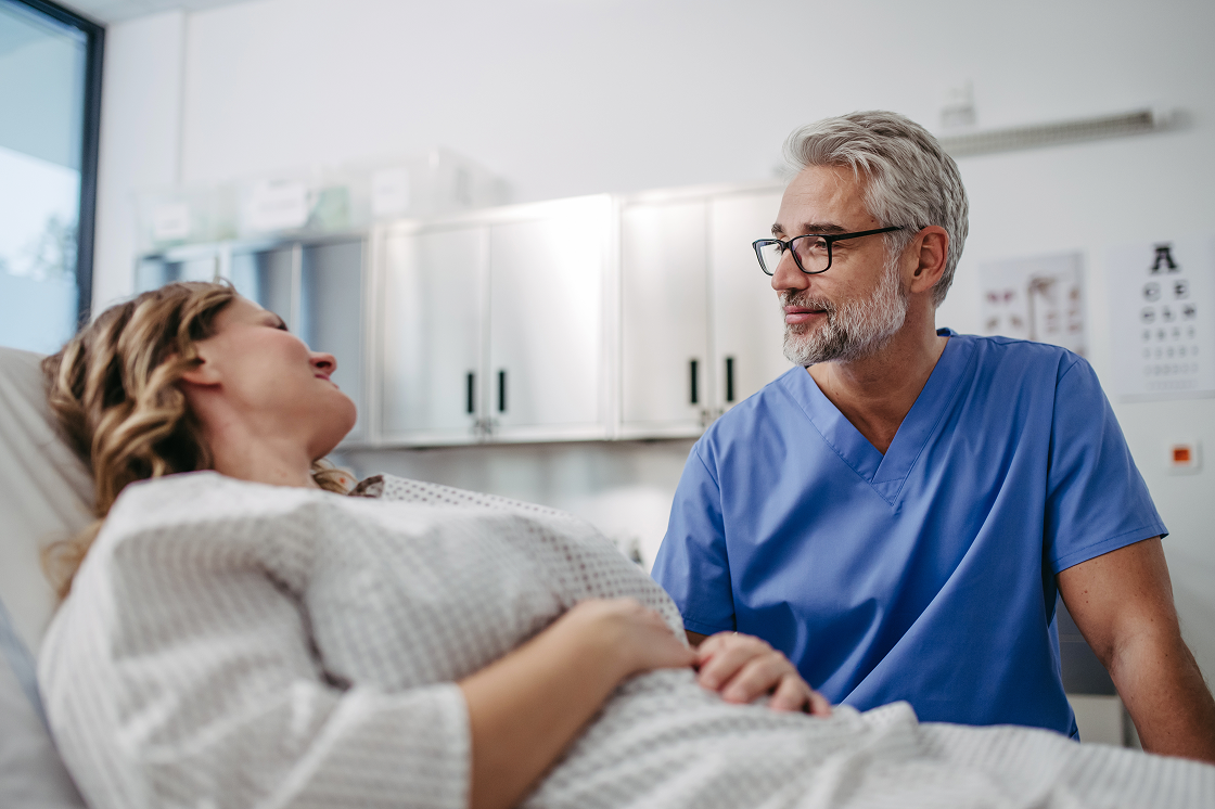 Ein Arzt im Gespräch mit einer Patientin in einem Behandlungszimmer