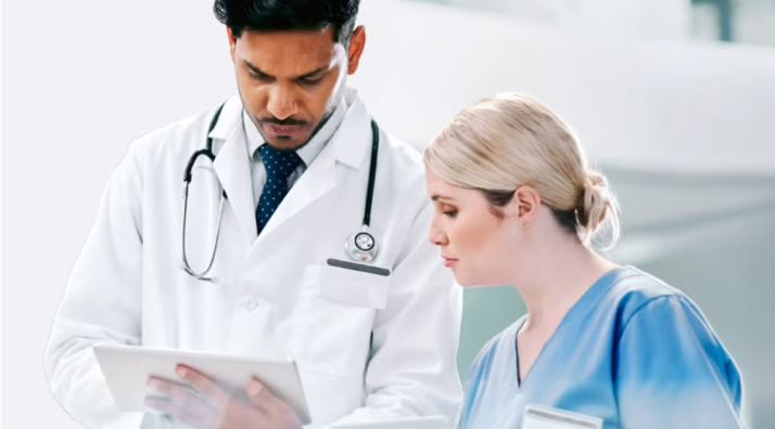 Medizinische Fachkräfte besprechen gemeinsam Patientendaten auf einem Tablet.