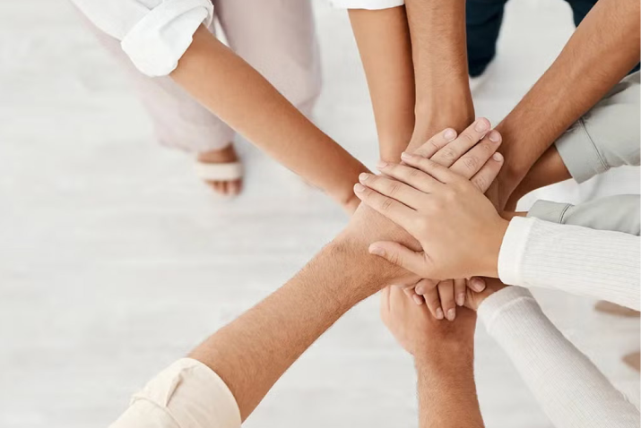 Mehrere Menschen legen ihre Hände übereinander als Symbol für Teamwork und Zusammenhalt