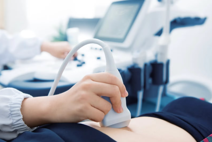 Nahaufnahme einer Ultraschallsonde, im Hintergrund das Ultraschallgerät