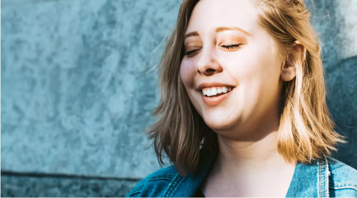 Lächelnde junge Frau mit geschlossenen Augen im Sonnenlicht