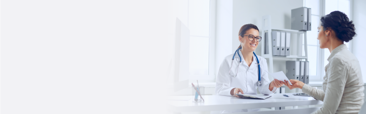 Eine junge Ärztin überreicht einer Patientin in der Praxis eine Notiz