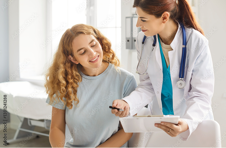 Ärztin, die ihrer Patientin auf einem Klemmbrett etwas zeigt