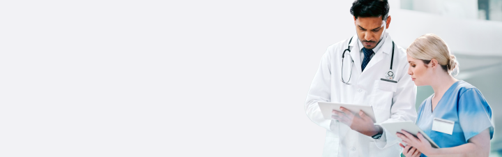 Ein Arzt und eine Pflegerin besprechen gemeinsam eine Patientenakte